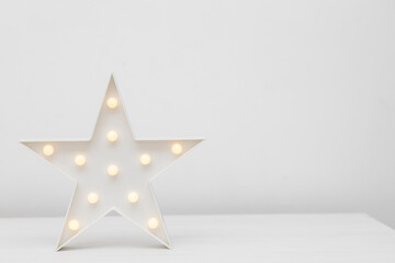 Table lamp nightlight in the form of a star on a white table on a white background. Copyspace. Place for text.