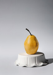Ripe pear standing on an inverted bowl