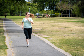 Mujer deportista entrenando, trotando y sonriendo en un parque urbano en un hermoso día soleado	