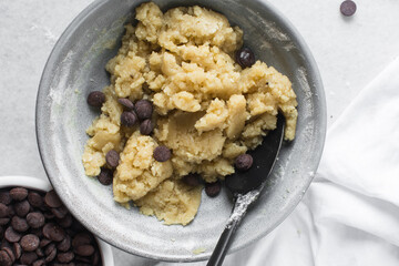 Overhead view of chocolate chip cookie dough, top view of homemade chocolate chip cookie dough in a bowl on a white background, process of making chocolate chip cookies