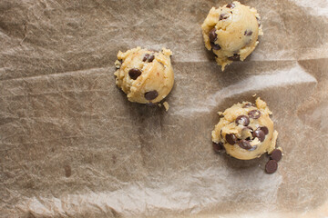 scoops of chocolate chip cookie dough on a baking sheet, homemade chocolate chip cookie dough, process of making chocolate chip cookies