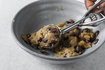 Overhead view of scooped chocolate chip cookie dough, top view of homemade chocolate chip cookie dough in a bowl on a white background, process of making chocolate chip cookies