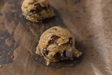 scoops of chocolate chip cookie dough on a baking sheet, homemade chocolate chip cookie dough, process of making chocolate chip cookies
