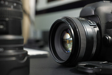 Professional camera and lens on black desk, selective focus