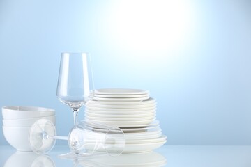 Different clean dishware on light blue background. Space for text