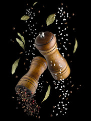 Salt and pepper mills in air on black background