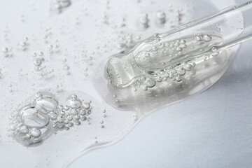 Pipette with cosmetic serum on light background, closeup