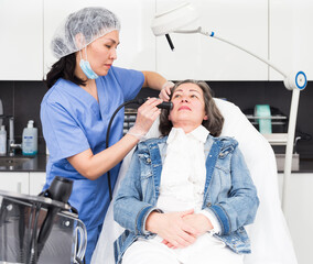 Elderly female client receiving hardware mesotherapy to revitalize and tighten facial skin at...