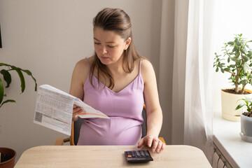 pregnant woman with calculator, computer pays utility bill. Receiving maternity benefits, social...