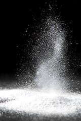 Dynamic display of falling white powder against a stark black background