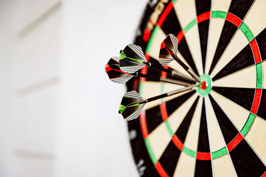 Close-up of three darts hitting the bullseye on a dartboard, showcasing precision and skill