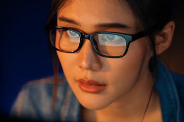 Portrait young beautiful Asian creative with glasses of serious face looking on pc to search project creator social media online, planning strategy creator at neon modern office at night. Stratagem.