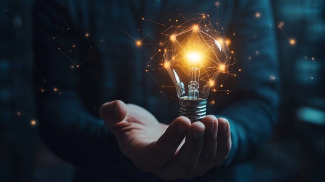 A man holds a glowing light bulb. This represents ideas, new thinking, and inspiration in business. It's also a symbol of digital data and ideas.