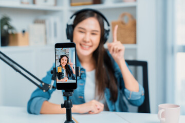 Selective focus phone in host channel of young beautiful Asian in creative broadcaster talking...