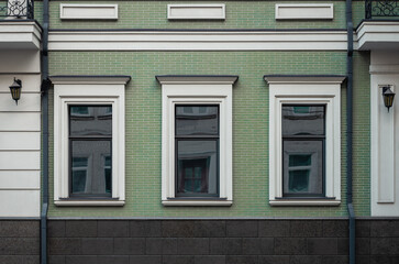 Facade of an old building. Building with green tiled facade and white window surrounds. Green house...
