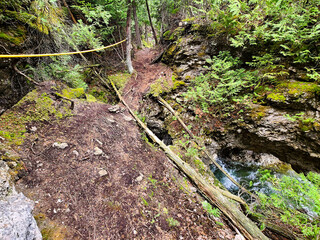A treacherous path across the top of a dolostone grotto and water below, surrounded by rocks,...