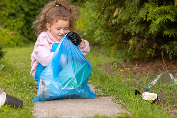 Girl collection plastic garbage in nature. kid picking up trash in park. Earth Day April 22. Save...