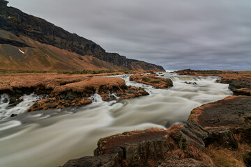 Powerful river flowing through rocky landscape under cloudy sky in iceland