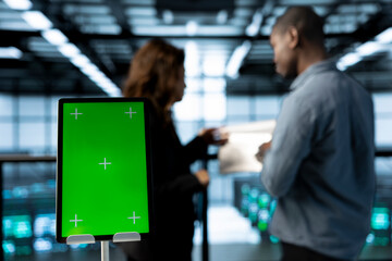 Green screen mockup tablet in front of technicians in blurry background working in server farm, analyzing data. Close up of chroma key tablet next to workers supervising data center