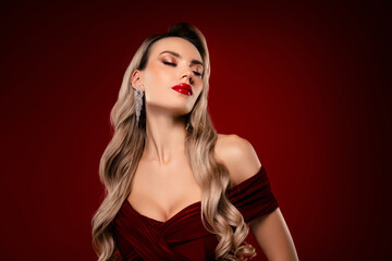 Fototapeta premium Elegant blonde woman with glamorous makeup and evening dress on burgundy background