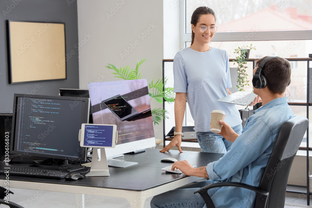 Poster young couple of programmers working at table in office