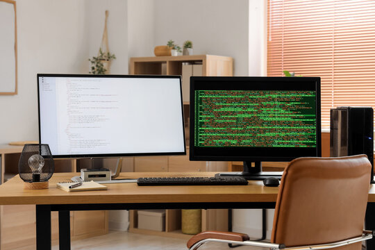 Modern workplace of programmer with double monitor in stylish office