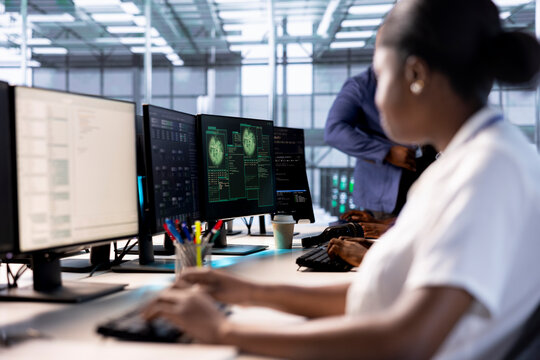 Computer scientist reconfiguring server farm to optimize it for data processing requirements of customers. African american woman working to ensure data center equipment operates efficiently