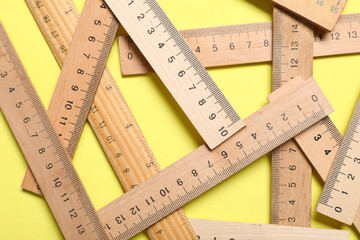 Wooden rulers on yellow background