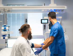 Obraz premium Doctor measuring blood pressure of patient in hospital room