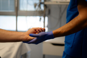 Doctor holding patient's hand providing comfort and reassurance in hospital room