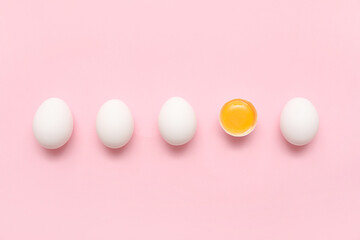 Whole and cracked chicken eggs on pink background