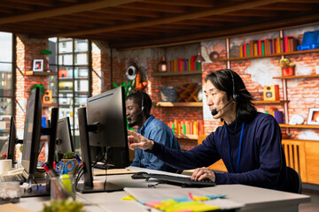 Team of call center agents at office desk handling customer inquiries, complaints and support requests. Customer service coworkers assisting clients with issues related to products