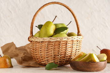 Wicker basket and wooden bowl with sweet ripe pears on white background