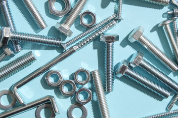 Different tap bolts and chrome nuts on blue background