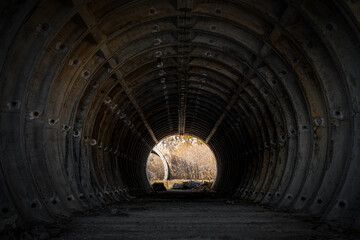 A dark tunnel in an abandoned concrete cylindrical structure. Ruins of old Soviet military...