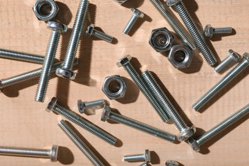 Tap bolts and chrome nuts on wooden background