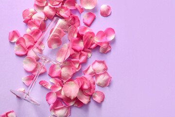 Glass with beautiful pink rose petals on purple background
