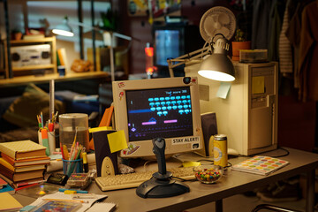Scene of classic arcade game on retro computer in cozy home office. Desk cluttered with office...