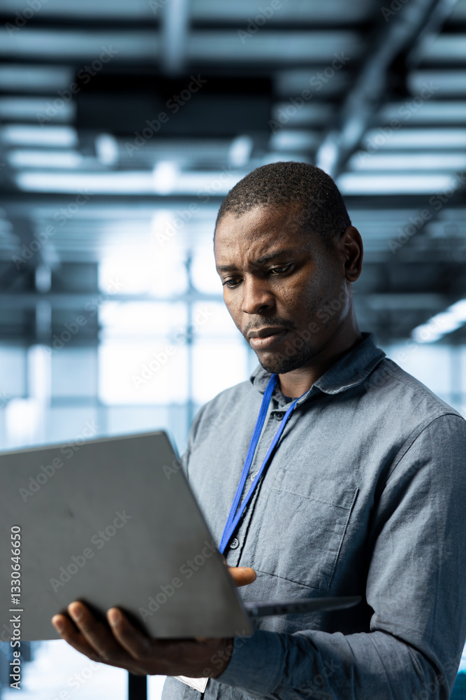 Poster engineer in data center using laptop, adjusting power management settings, verifying compliance requ