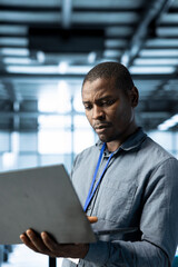 Engineer in data center using laptop, adjusting power management settings, verifying compliance...