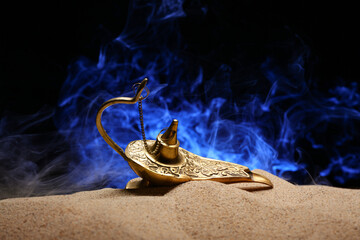 Lamp of Aladdin with fume and sand on dark background