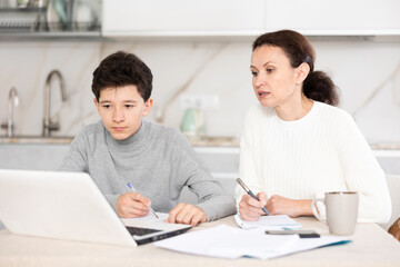 Boy and mother studiyng and learning together using laptop