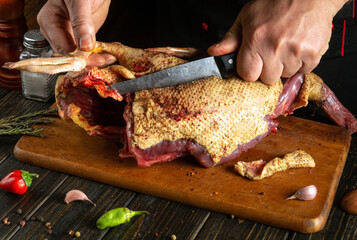 Preparing duck meat for a rich broth. The chef's hands skillfully wield a knife, cutting the bird into pieces.