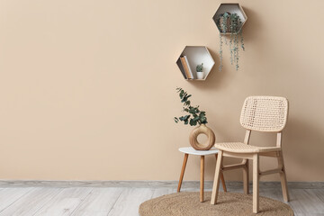 Comfortable wooden chair with coffee table, vase of eucalyptus branches and houseplants near beige wall