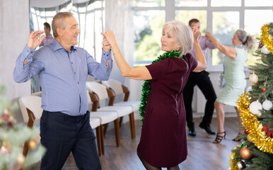 Group of adult active people dancing twist or rock and roll dance in modern dance hall during celebration Christmas and New Year