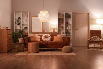 Interior of modern living room with brown sofa, armchair, shelving units and glowing lamps at...