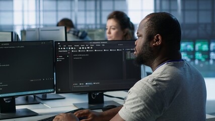 Admin in server hub tasked with protecting valuable data against hacking attack on computers. African american worker safeguarding data center against unauthorized access and vulnerabilities, camera A