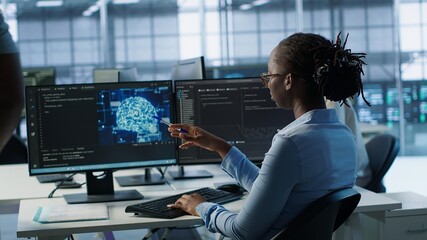 Engineer waiting at PC desk for checkup to be done on AI server room providing computing resources....
