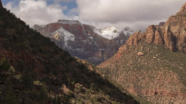 4k time lapse video of West Temple Mt. in Zion NP Ut. USA on a March day with a light layer of fresh snow on the higher elevations and clouds drifting past casting shadows on the landscape.