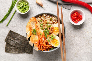 Bowl of ramen noodle soup with chicken and korean carrot salad on white background